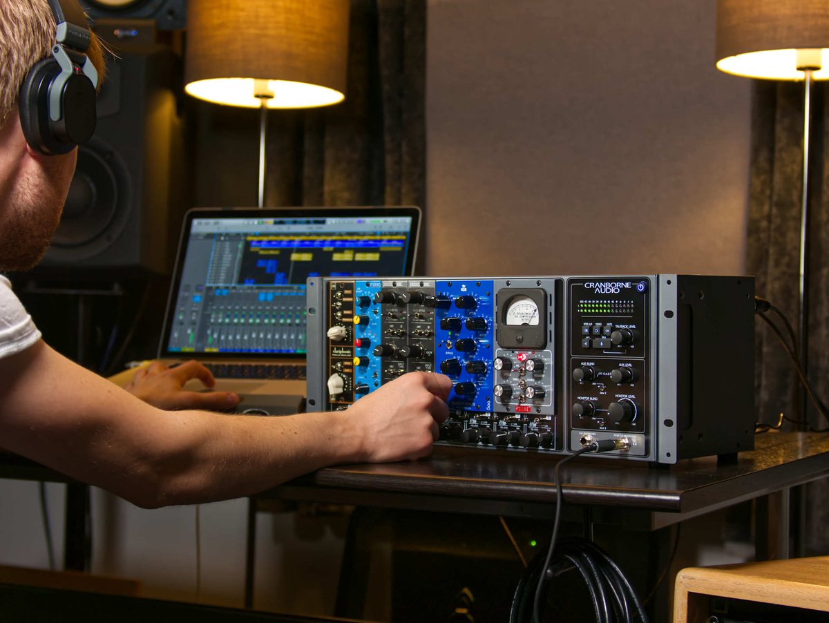 500 series rack with modules in a home studio setup next to monitors and audio interface